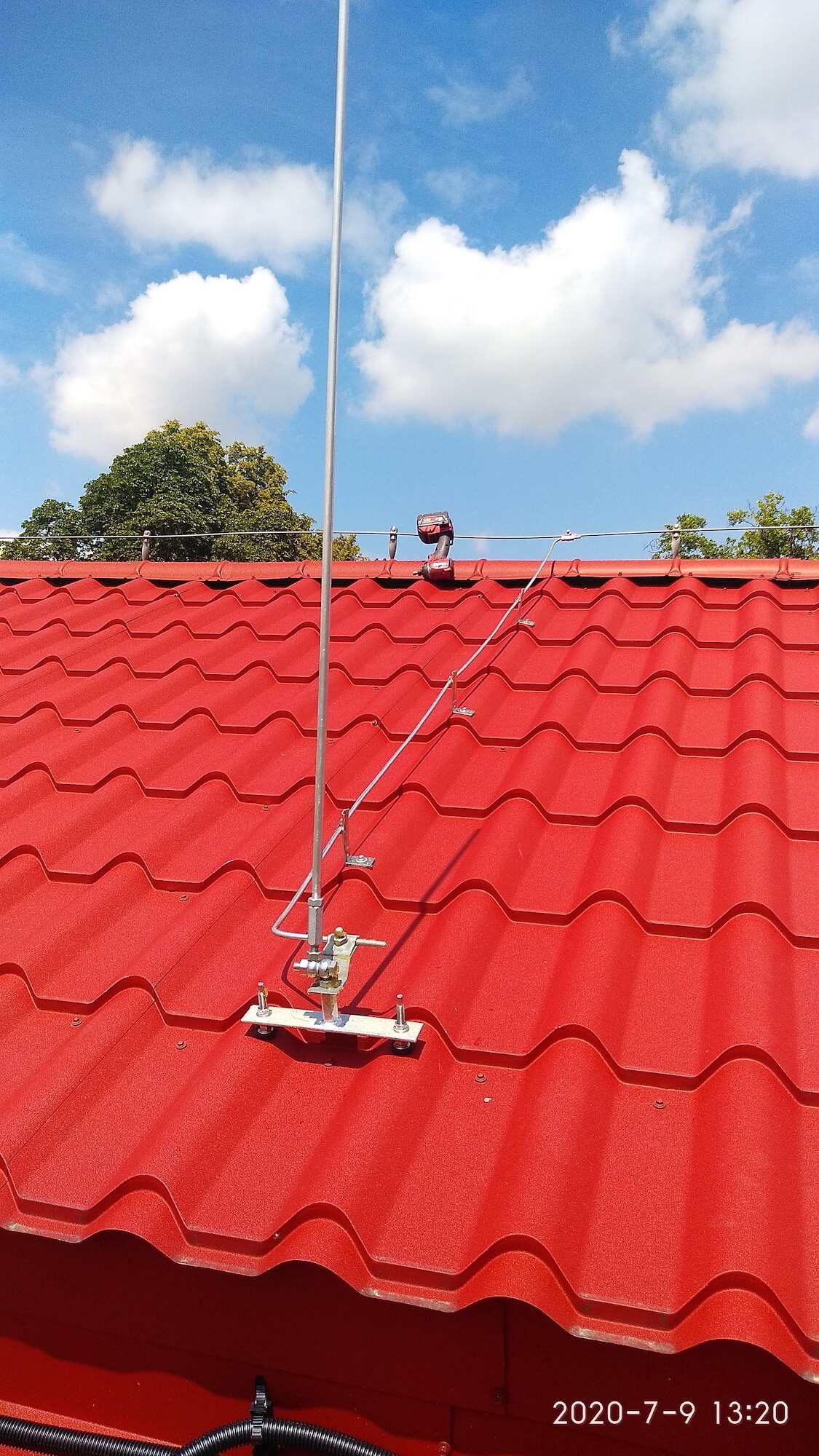 A lightning rod with adjustment to verticality in relation to the slope of the roof, screwed to the structure of the roof covered with steel tiles. FeZn wire guided on screwed angular holders and ridge tile holders